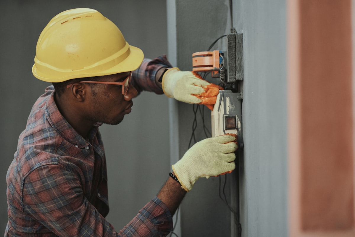 Technician in a hard hat servicing a wall fixture